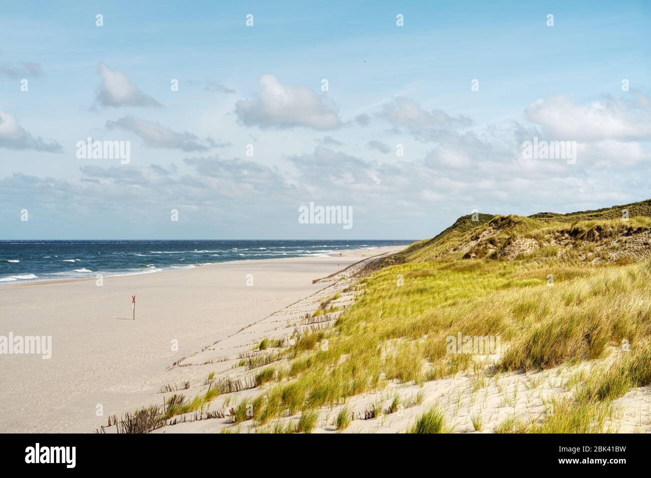 Heller Sandstrand und grasbewachsene Dünen am blauen Meer. Sommer-Landschaftspanorama auf der Insel Sylt, Nordfriesische Inseln, Deutschland. Kopierbereich. Stockfoto