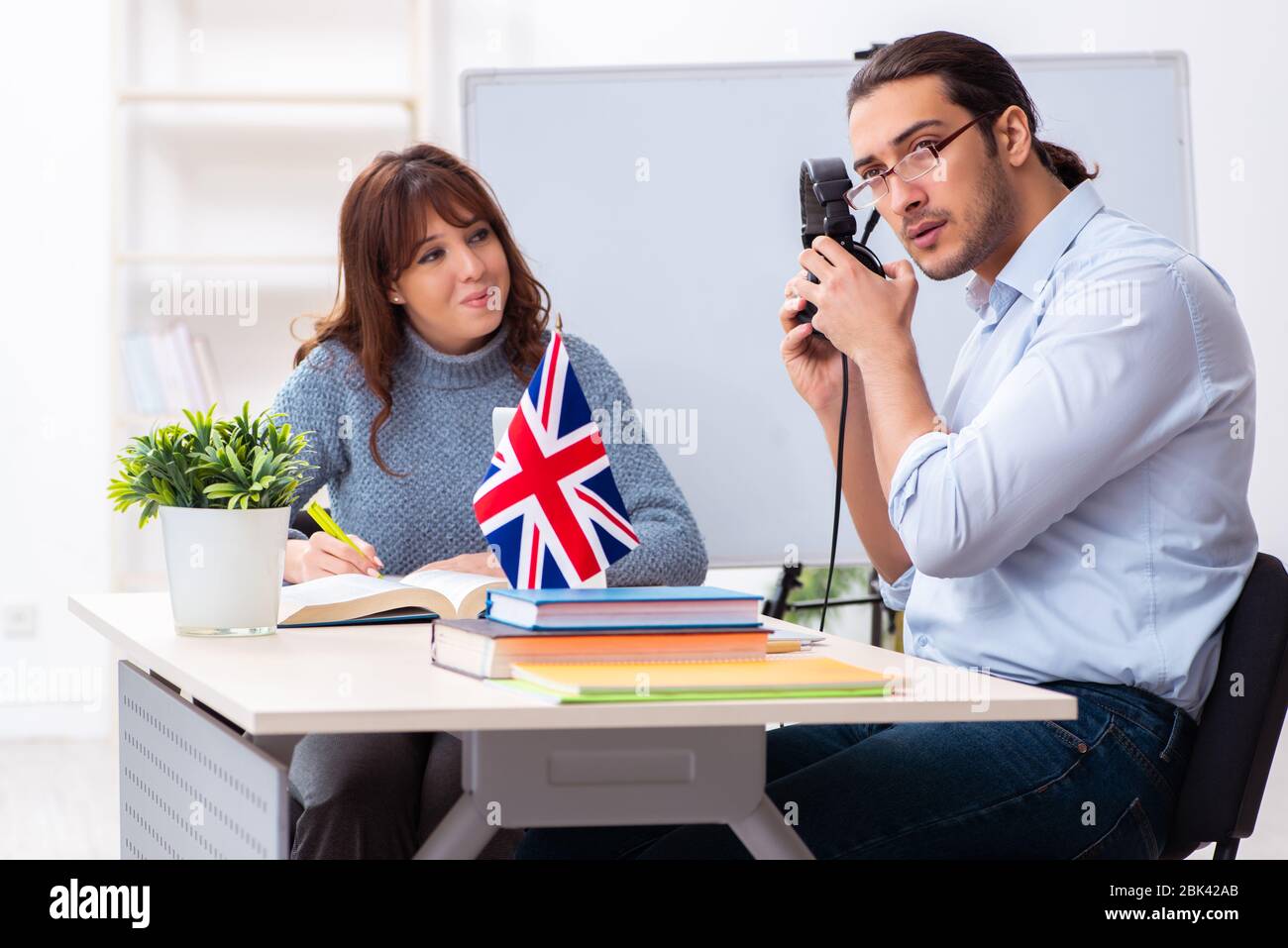 Junger Schüler und männlicher englischlehrer im Klassenzimmer Stockfoto