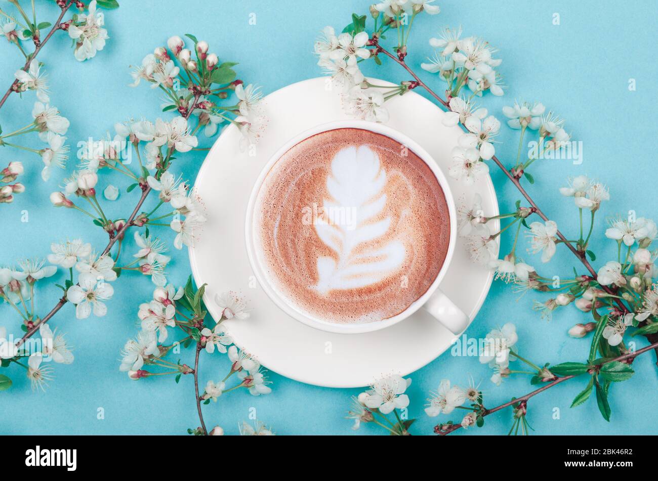 Kaffeetasse mit Latte Art und Frühlingskirschenblüte Stockfoto