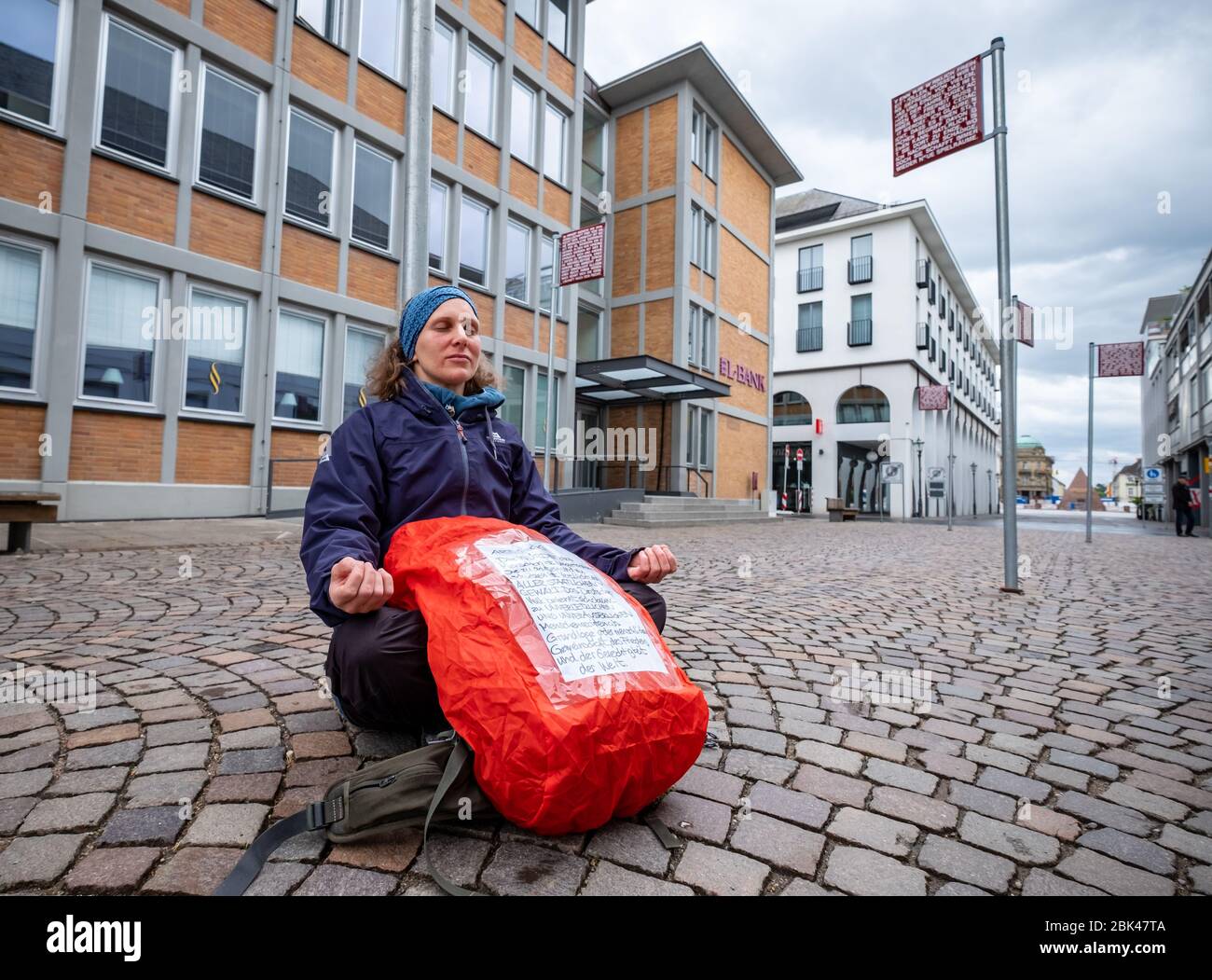 Deutschland. Mai 2020. In Karlsruhe, am Platz für Grundrechte, gibt es Straßenschilder mit Aussagen zum Thema Recht (Kunstwerk von Jochen Gerz). Eine Frau sitzt auf einem der Zeichen mit dem Plakat der Grundrechte und meditiert. GES./ Alltag in Karlsruhe während der Koronakrise, 01.05.2020 Ges./ Alltag während der Koronakrise in Karlsruhe. 01.05.2020 Kredit: dpa/Alamy Live News Stockfoto