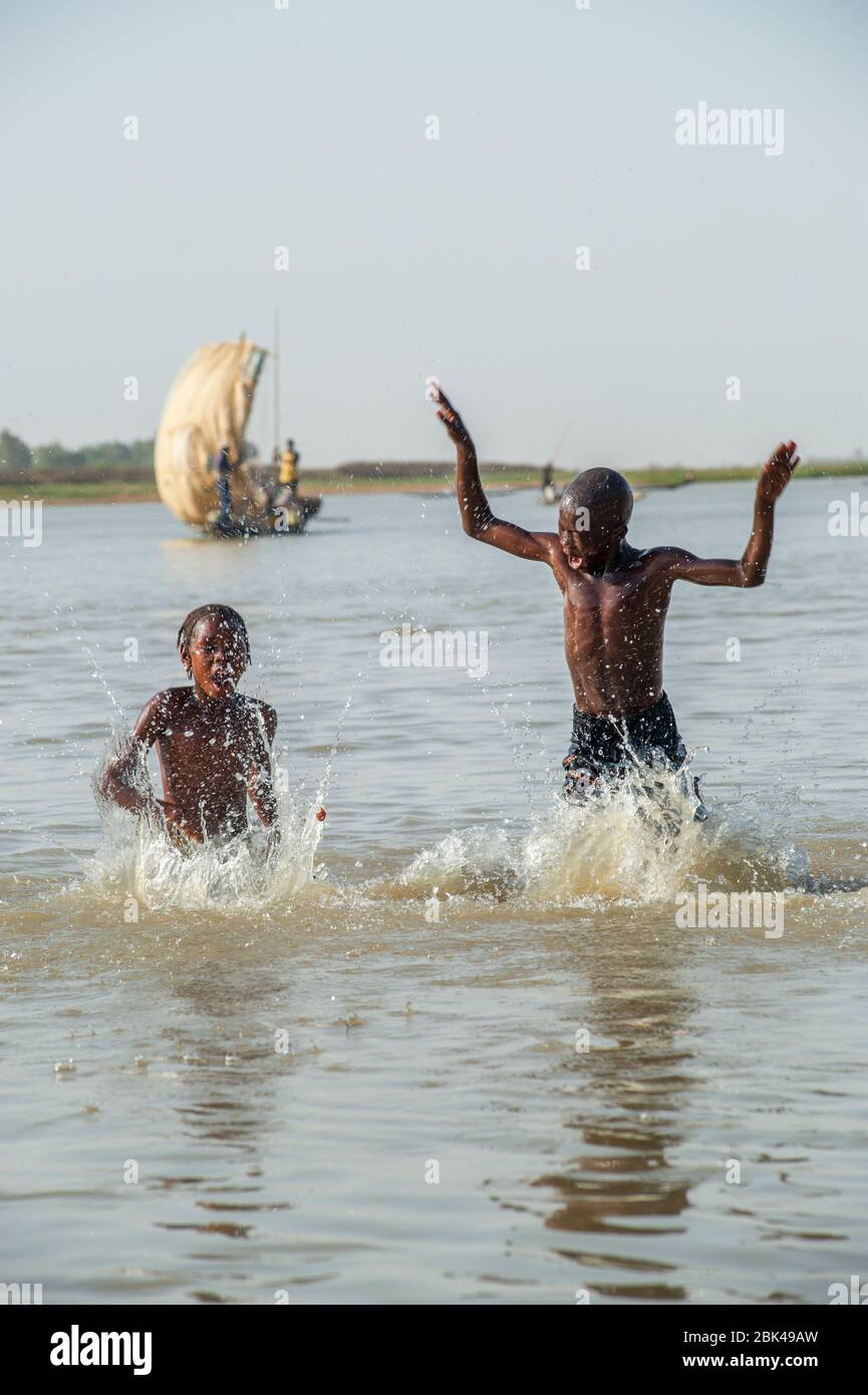 Ein Junge und ein Mädchen spielen und planschen im Wasser des Bani-Flusses in Mopti in Mali, Westafrika. Stockfoto