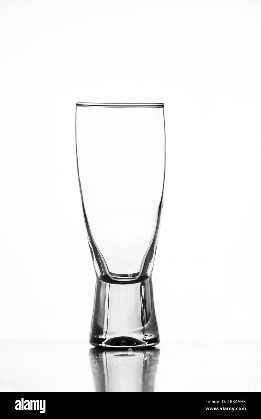 Leeres Bierglas mit Spiegelung auf dem Tisch und weißem Hintergrund Stockfoto