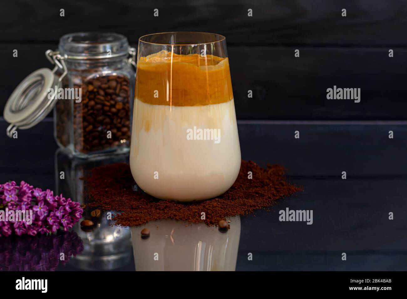Dalgona Kaffee ist ein trendiges kaltes koreanisches Getränk. Geschmackvoller, aromatischer Kaffee mit Milch und Zucker in einem Glas auf schwarzem Hintergrund. Kopierbereich Stockfoto
