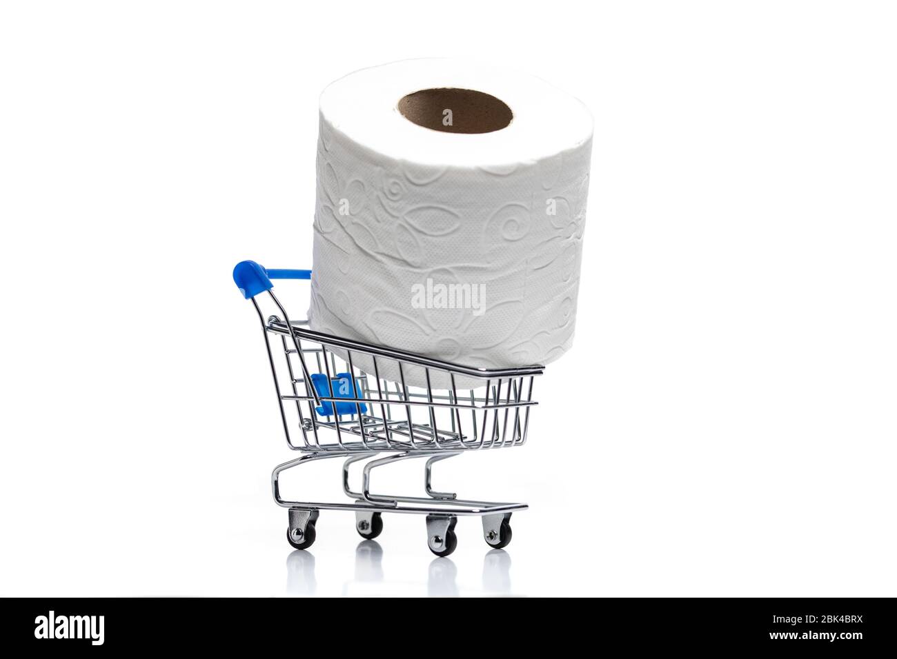 Lebensmitteleinkaufwagen mit Toilettenpapierrollen dahinter. Konzept des Mangels an Toilettenpapier in den Geschäften aufgrund Coronavirus, Covid-19 Stockfoto