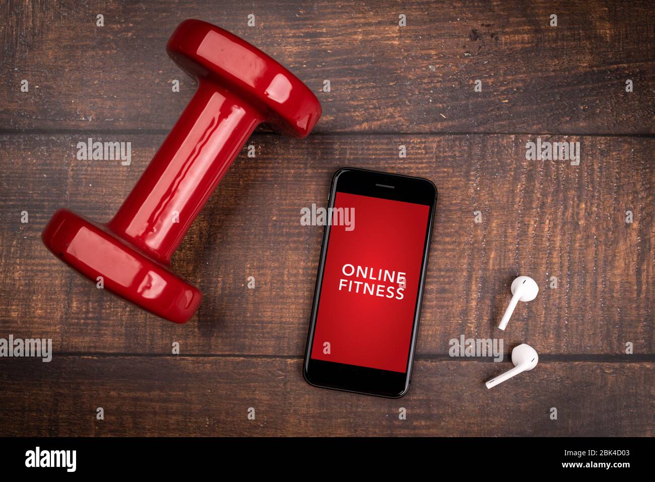 Rote Hantel und Smartphone auf einem Holzhintergrund. App für das Training in Innenräumen. Online-Fitnessprogramm. Home Online-Workout. Draufsicht, Covid-19 Coronavi Stockfoto