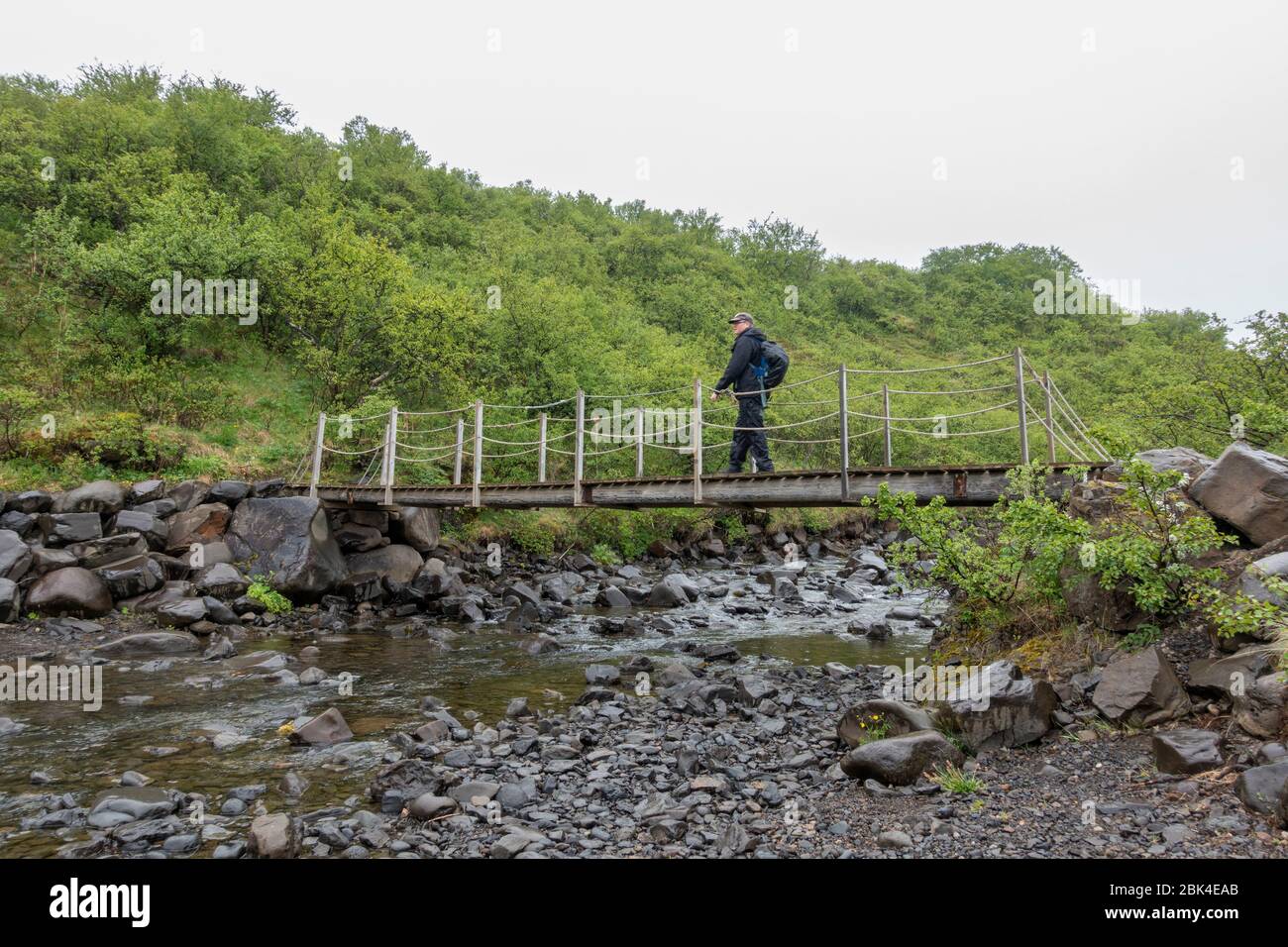 Ein Mann, der über eine kleine Brücke in der Nähe von Skaftafell, Vatnajökull Nationalpark, Süd-Island. Stockfoto