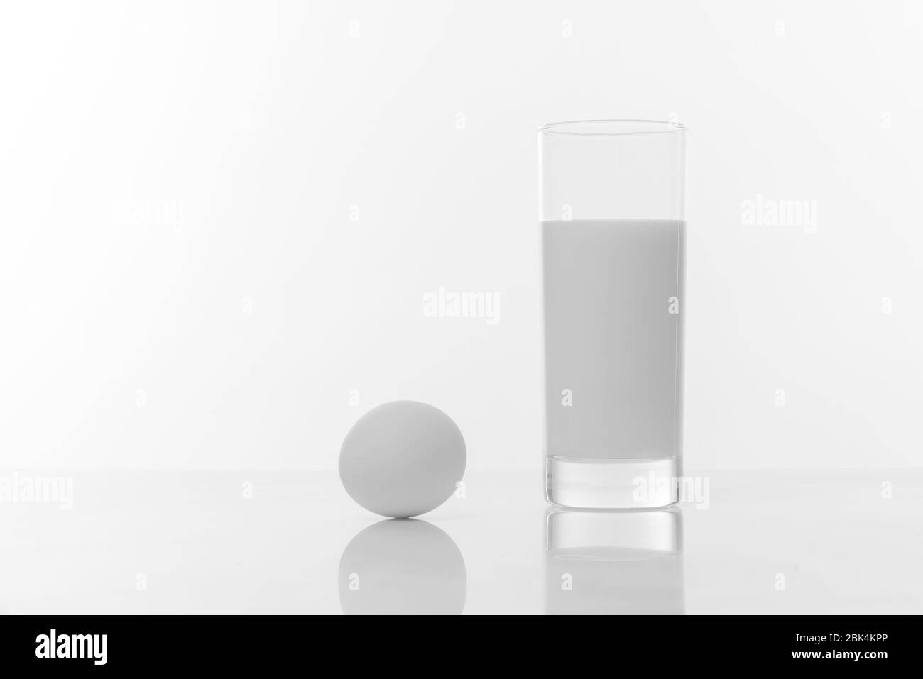 Schwarz-Weiß-Foto von einem Glas reiner Milch und Hühnerei isoliert ob weißen Hintergrund Stockfoto