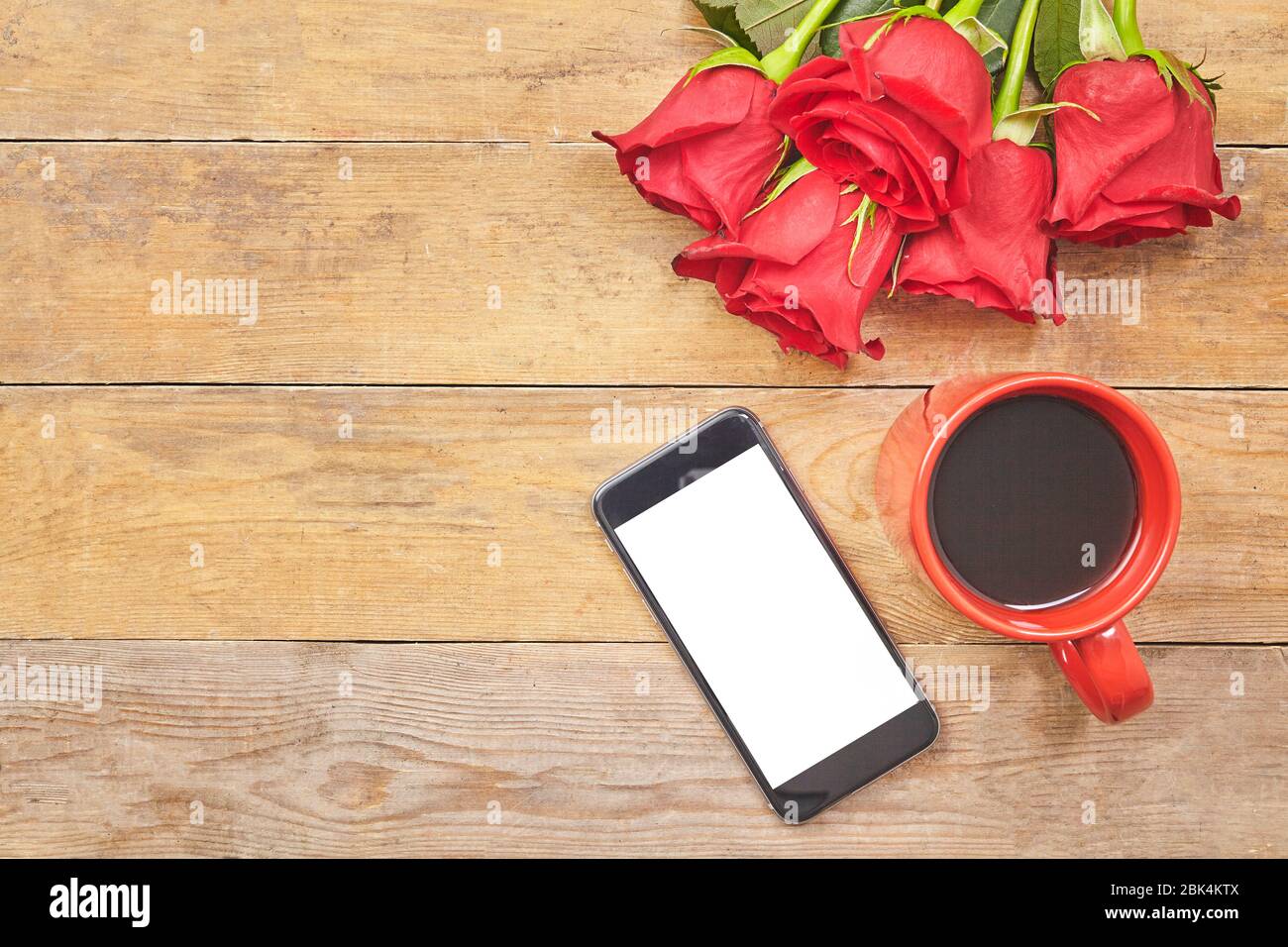 Draufsicht heißer Kaffee Latte mit einer roten Rose und Smartphone auf einem Holztisch. Stockfoto