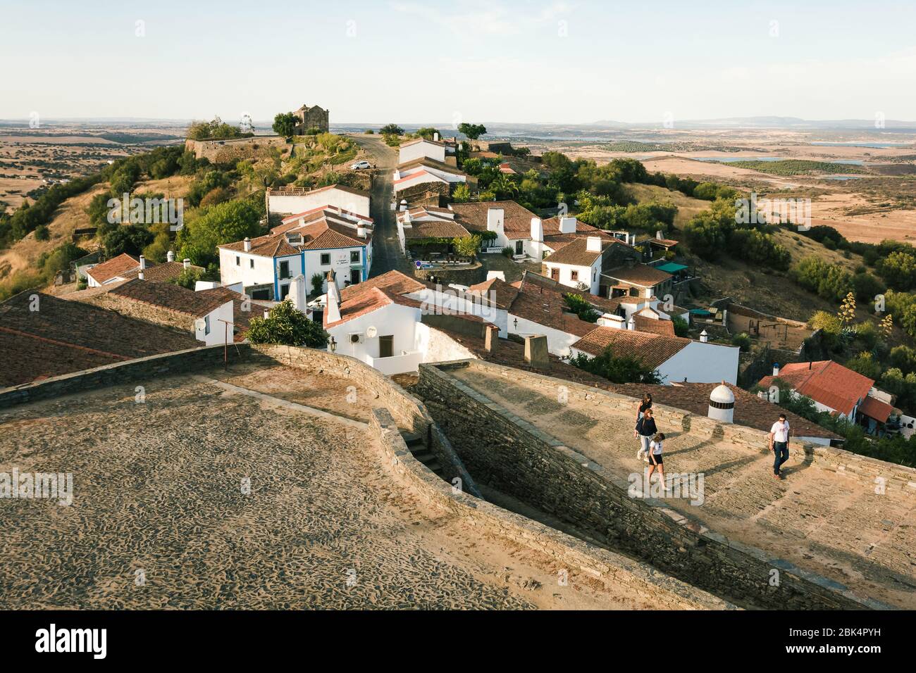 Blick auf Monsaraz, Portugal, malerisches Dorf in der Nähe der Alqueva-Staumauer, bei Sonnenuntergang, mit Touristen, typische Häuser aus Alentejo und Weizenfelder Stockfoto