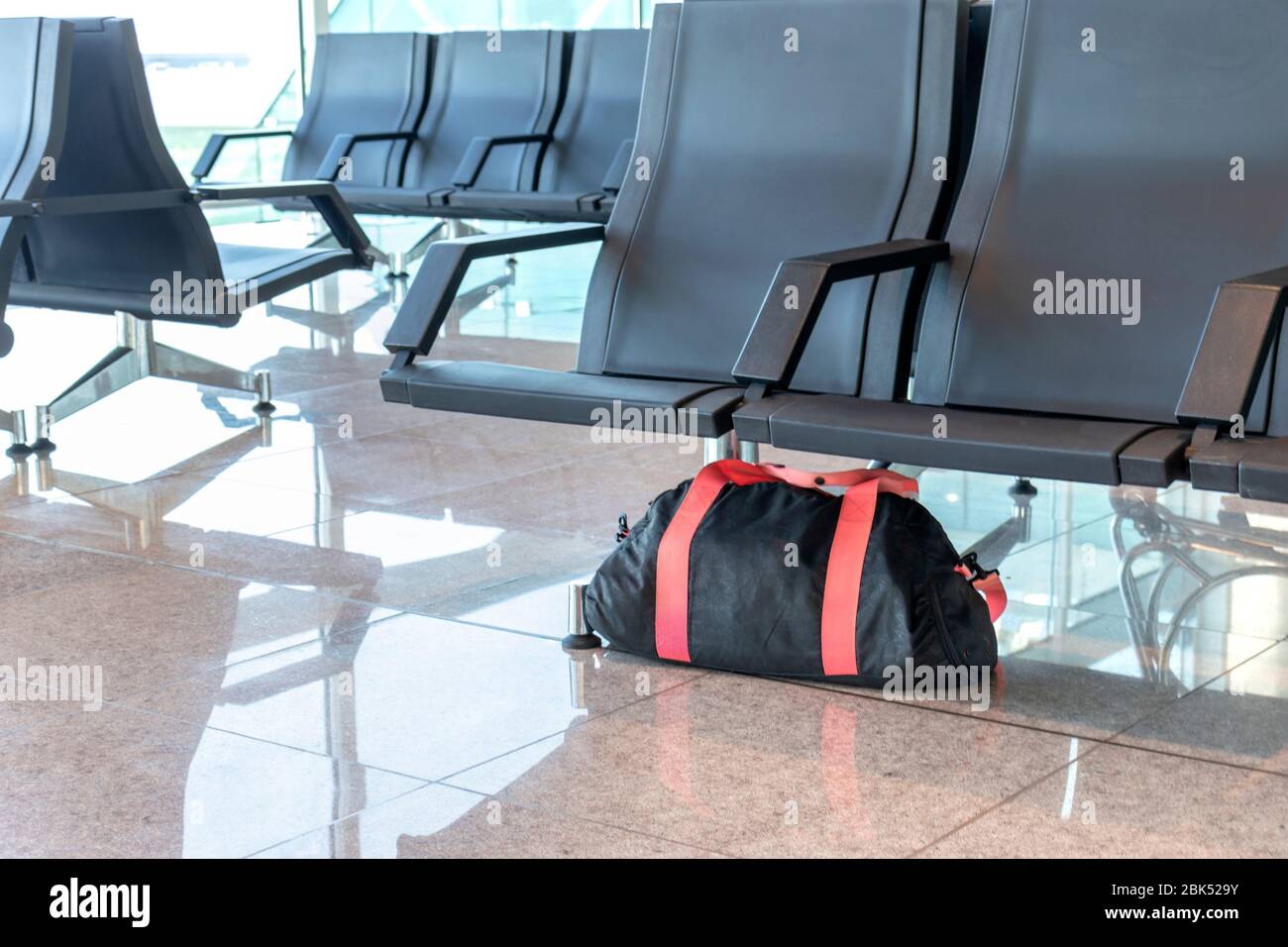 Verdächtige schwarze und rote Tasche unbeaufsichtigt unter dem Stuhl auf Bahnsteig am Bahnhof oder Flughafen gelassen. Terrorismus und Konzept der öffentlichen Sicherheit Stockfoto
