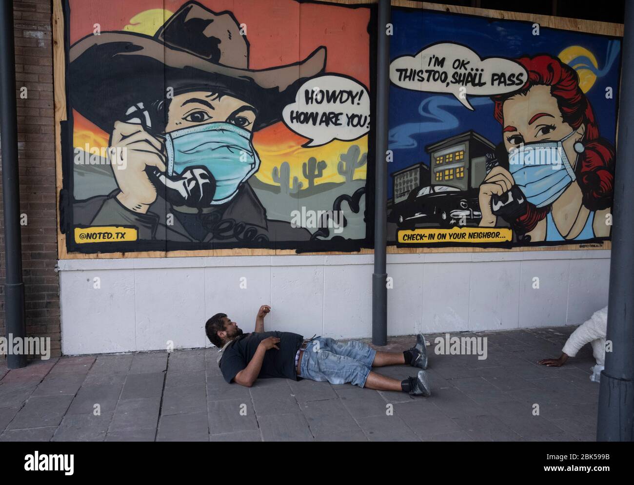 Der Mann liegt auf dem Bürgersteig vor bunten Wandmalereien schmücken vernagelt Bar und Restaurant Fronten auf der normalerweise belebten Sixth Street Entertainment District. In Austin, Texas, sechs Wochen nach einer Geschäftsabschaltung aufgrund der Coronavirus Pandemie. Stockfoto