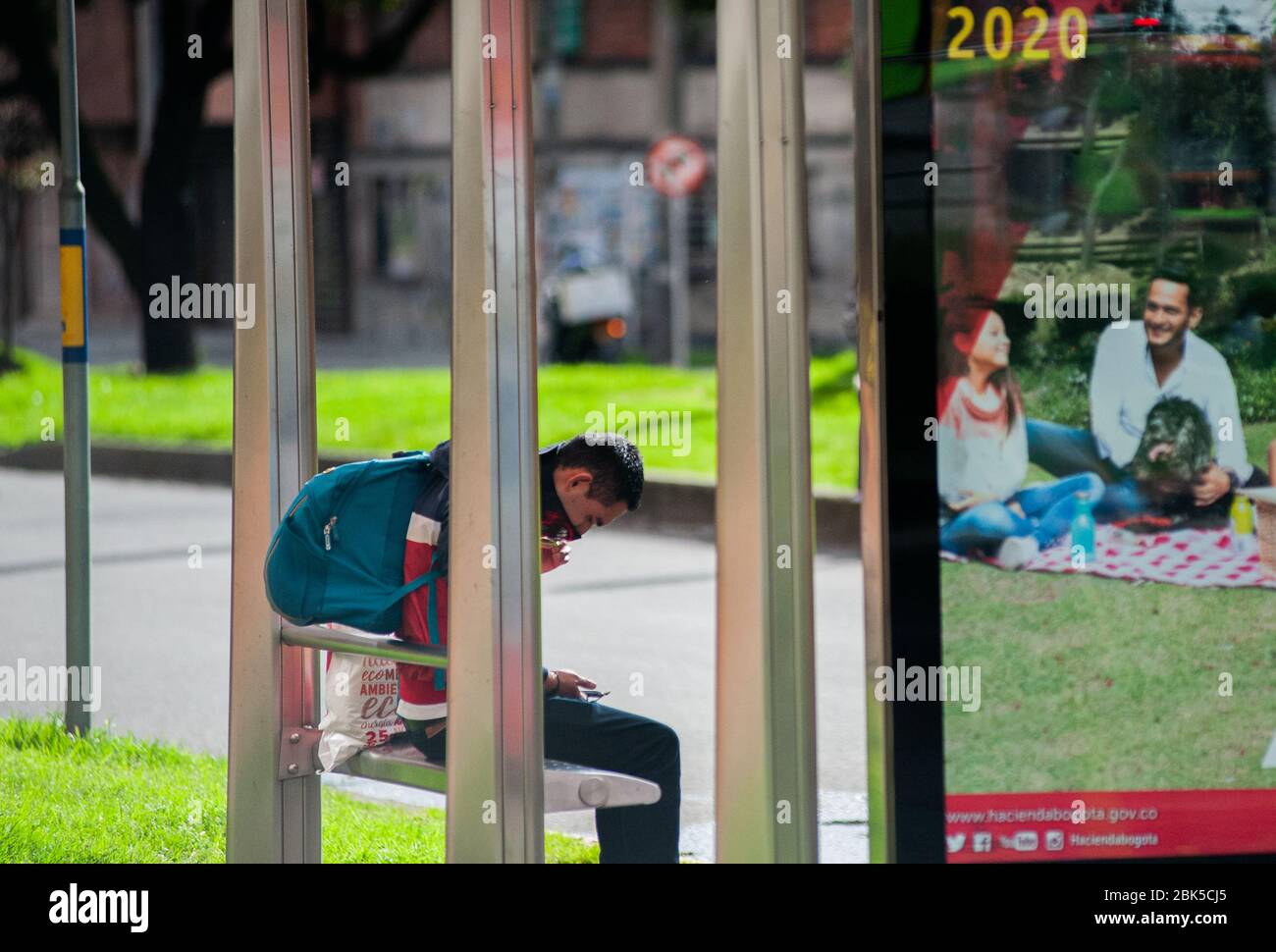 Ein Mann mit einer schützenden Gesichtsmaske wartet auf einen Bus inmitten der Coronavirus (Covid-19) Pandemie, die die Stadt Bogota unter Sperre gesetzt hat, mit Th Stockfoto