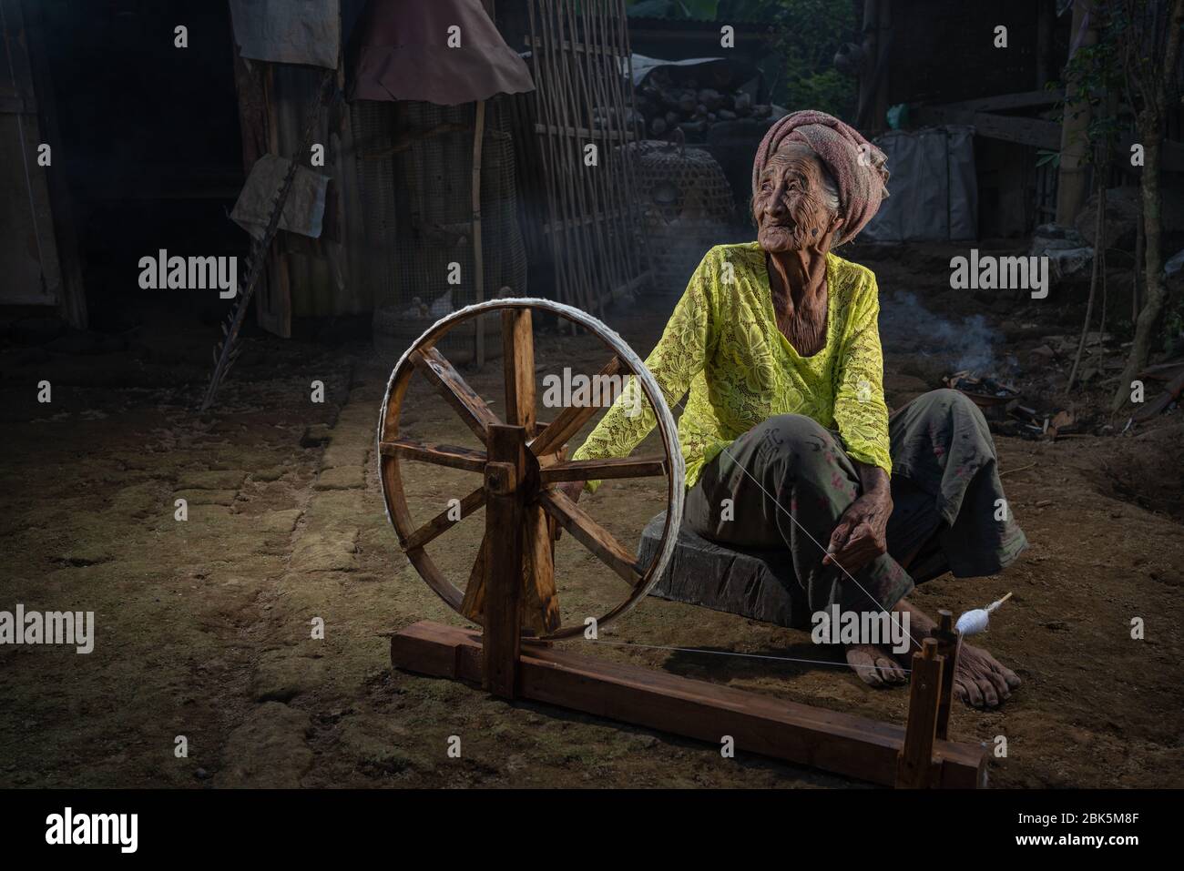 Ubud, Gianyar, Bali, Indonesien - 28. Juni 2019 : Alte balinesin mit Spinnrad in einem kleinen Dorf in der Nähe von Ubud. Stockfoto