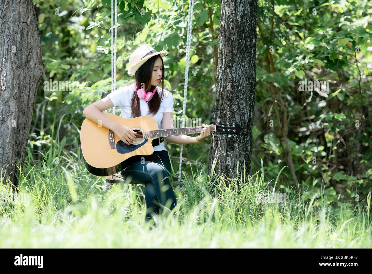 Schöne junge Frau mit Akustikgitarre im Naturhintergrund Stockfoto