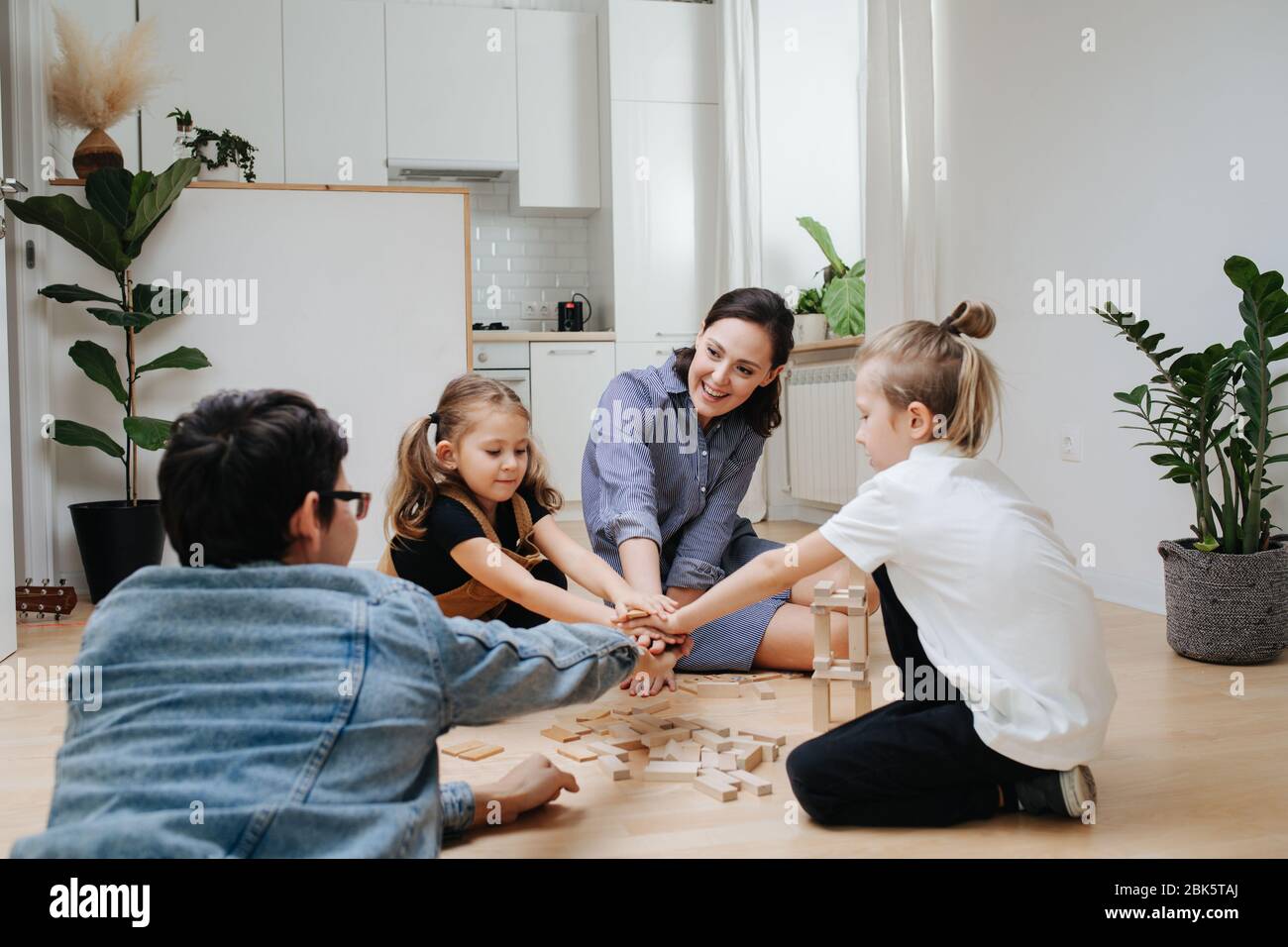 Mama, Papa und Kinder spielen Handspiel auf einem überladen Küchenboden Stockfoto
