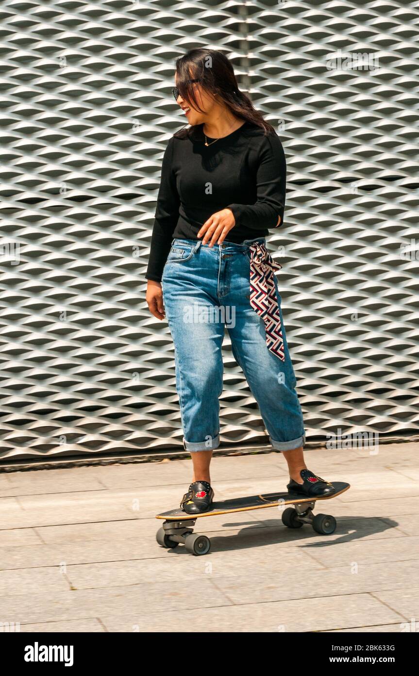 Eine junge Chinesin, die in der Nähe des Wasserfront vor dem Long Museum West Bund, Shanghai, China, Skateboarding macht. Stockfoto