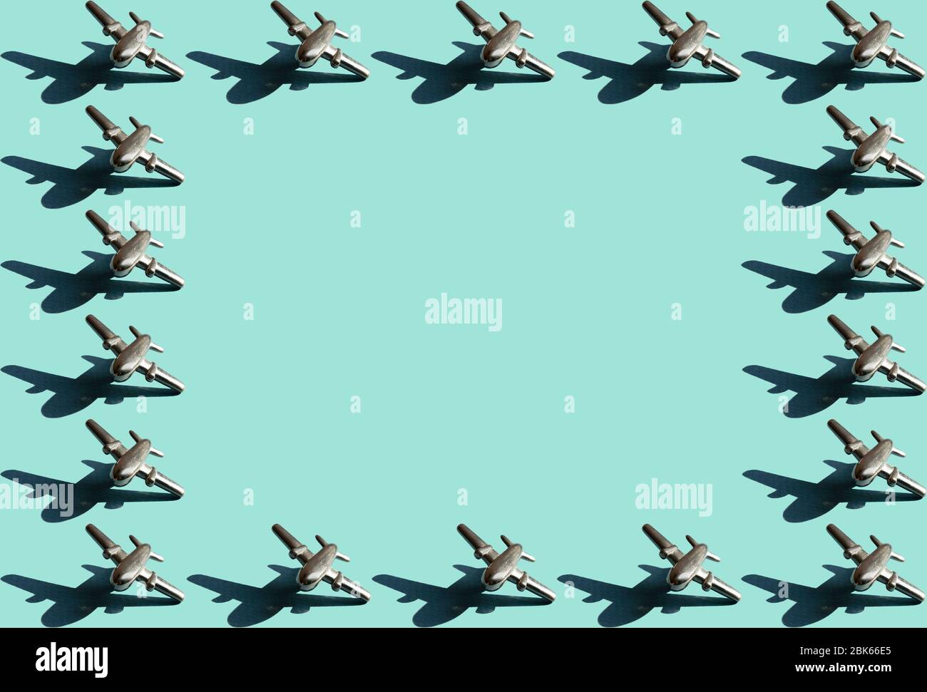 Rahmen aus einzehn Metallfiguren von kleinen Flugzeugen mit Schatten mit dem gleichen Raum zwischen ihnen auf dem hellen mintfarbenen Hintergrund. Konzeptionelle Geometr Stockfoto