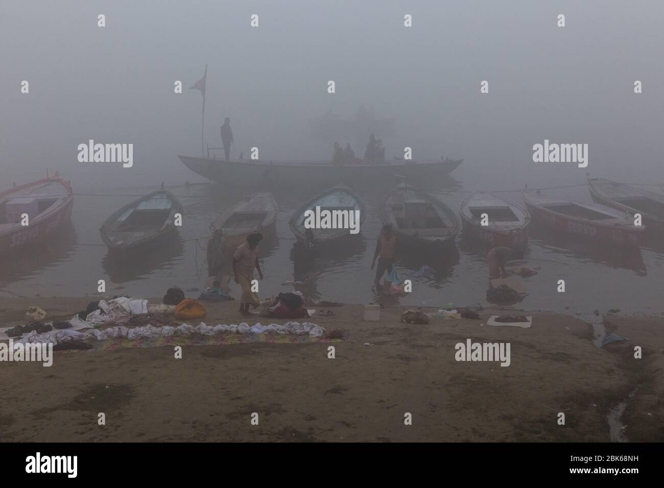Eine neblige morgendliche Bootsfahrt und Menschen waschen Kleidung in kühlen Morgen am Ufer des Flusses Ganges, Varanasi, Indien Stockfoto