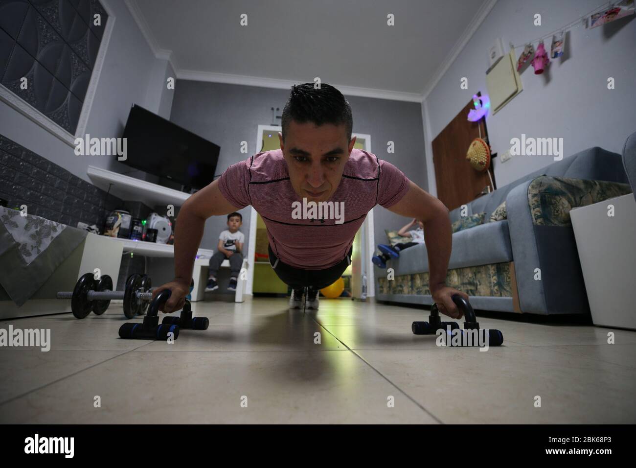 Jerusalem. Mai 2020. Fitness-Trainer und Bodybuilder Mohammad Shweiki zeigt eine Übung in seinem Haus während einer Blockade inmitten der COVID-19-Pandemie am 1. Mai 2020 in Jerusalem. Nachdem Israel nicht-essentielle Bewegung verboten und die Schließung aller Freizeit- und Unterhaltungsorte angeordnet hatte, um die Ausbreitung des COVID-19-Virus einzudämmen, machte Shweiki Videos und postete sie für seine Anhänger online. Kredit: Muammar Awad/Xinhua/Alamy Live News Stockfoto