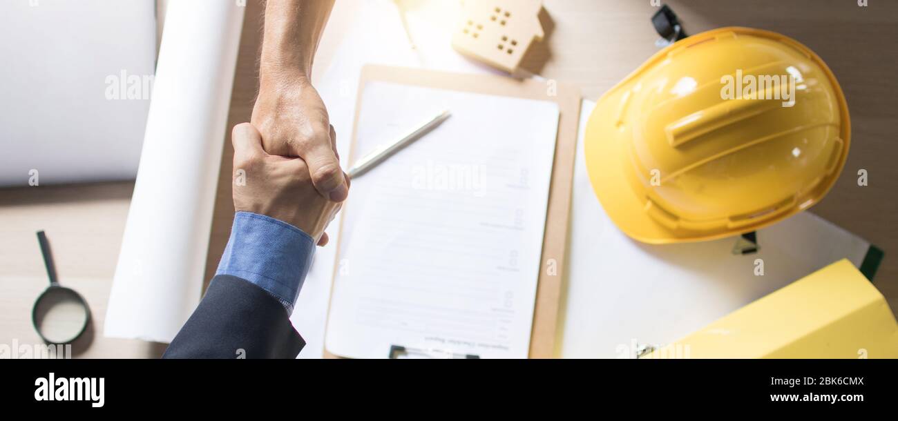 Draufsicht des Investors, Geschäftsmann schüttelt Hand mit Ingenieur oder Architekt auf Arbeitstisch auf der Baustelle, nach dem Abschluss der Diskussion und Sitzung Stockfoto