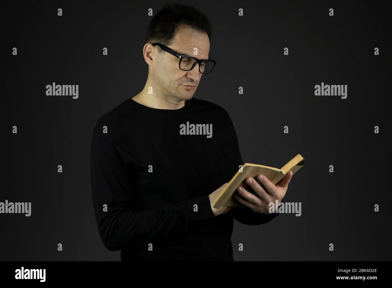 Schöner Casual gekleideter 40er Mann mit dunklen Haaren in Gläsern liest Buch Stockfoto
