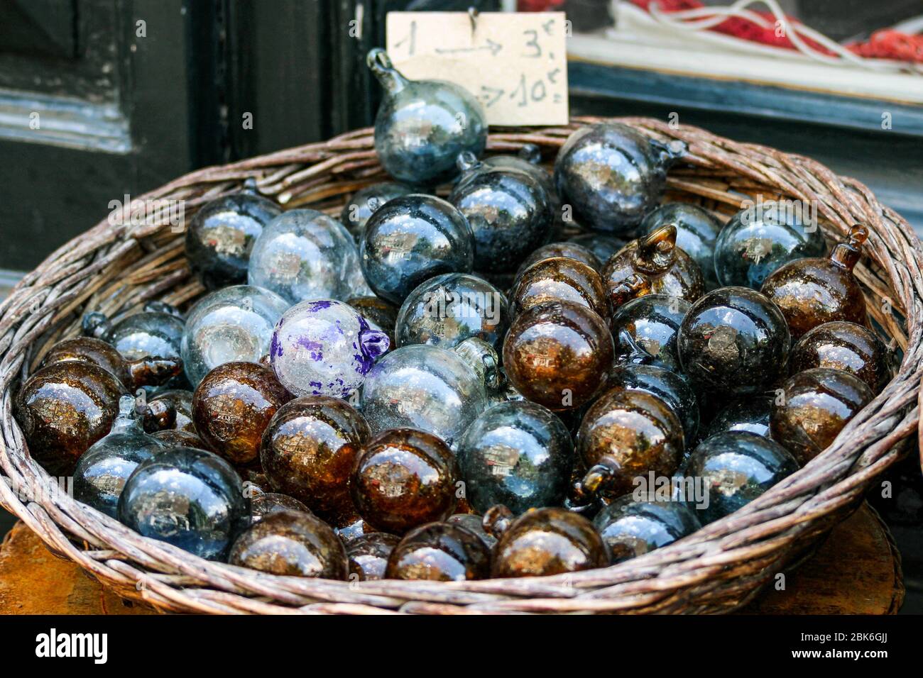 Mehrere Glasschmuck oder -Kugeln zum Verkauf in einem runden Korb Stockfoto