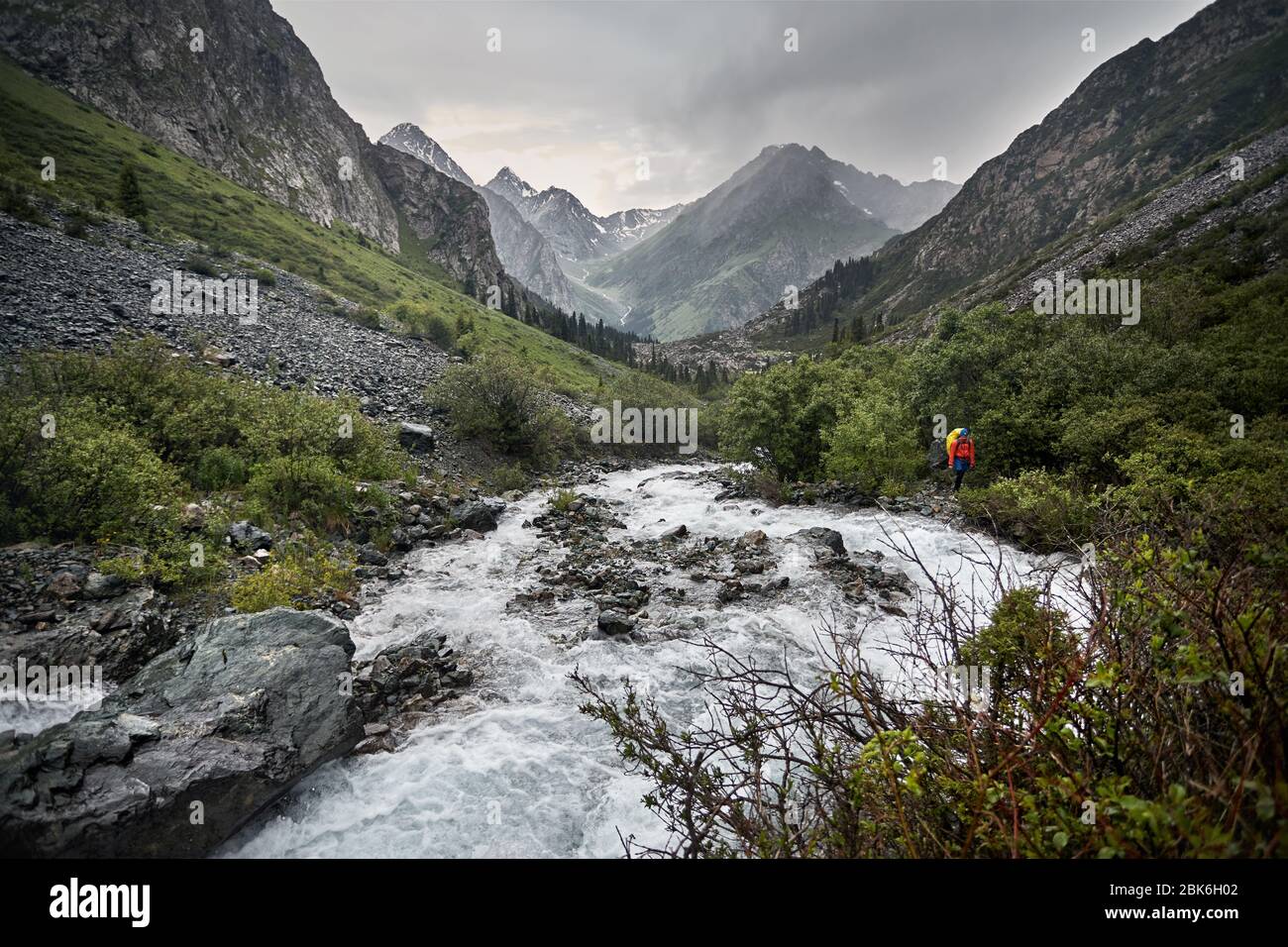 Wanderer mit gelben Rucksack in den Berg Tal mit Fluss und Rocky Mountains Nationalpark in Karakol, Kirgisistan Stockfoto