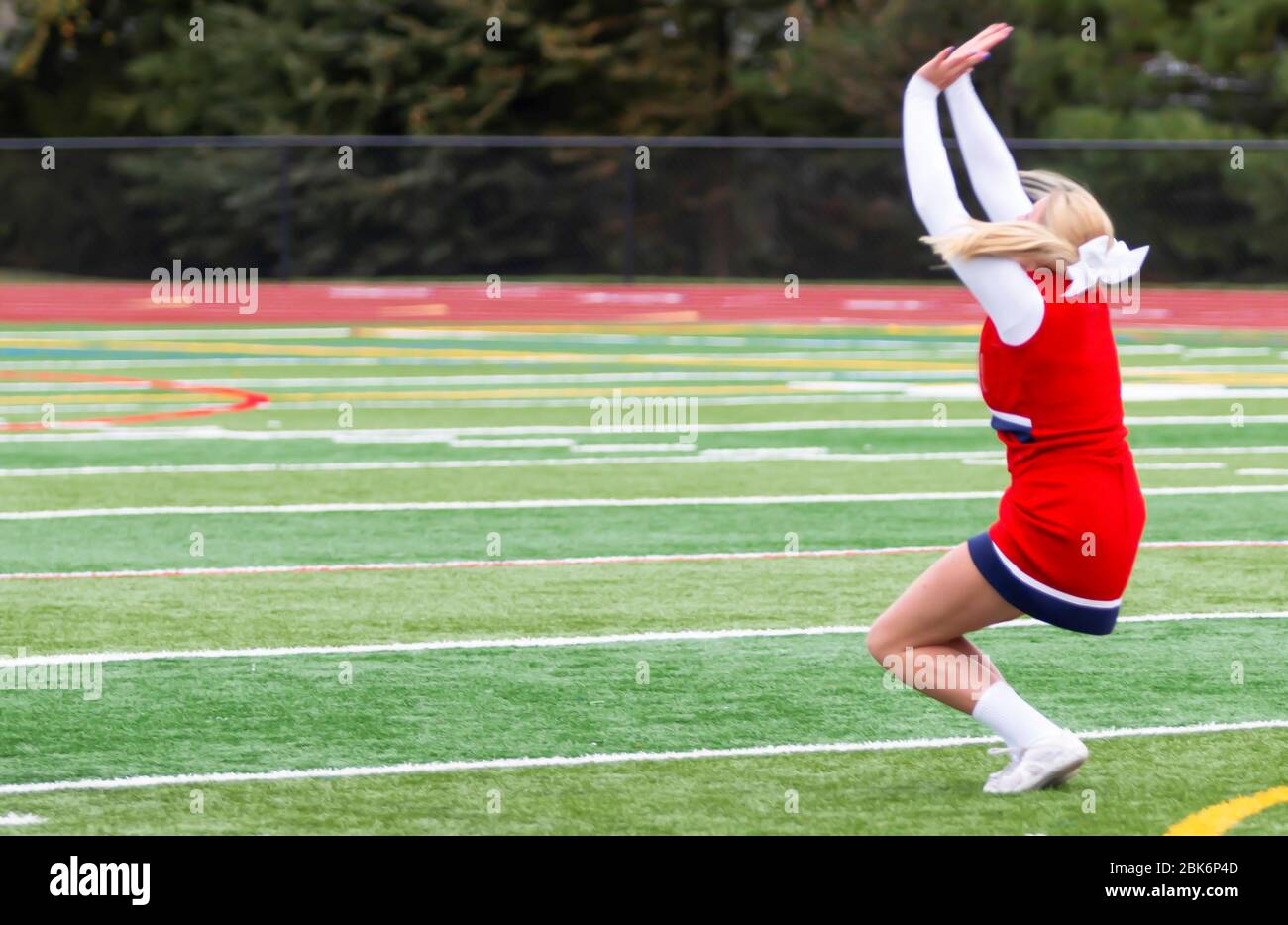 Ein Cheerleader der High School ist auf einem grünen Rasenfeld mit einem Gespult. Stockfoto