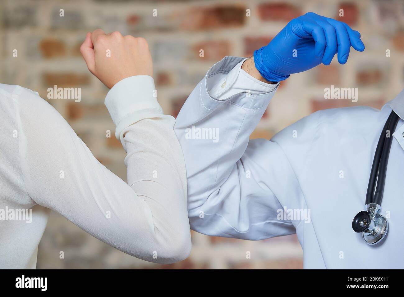 Eine neue Art der Begrüßung, um die Ausbreitung des Coronavirus zu vermeiden, COVID 19. Ein Arzt und eine Frau stoßen Ellbogen an, anstatt wieder mit einer Umarmung oder einem Handschlag zu grüßen Stockfoto