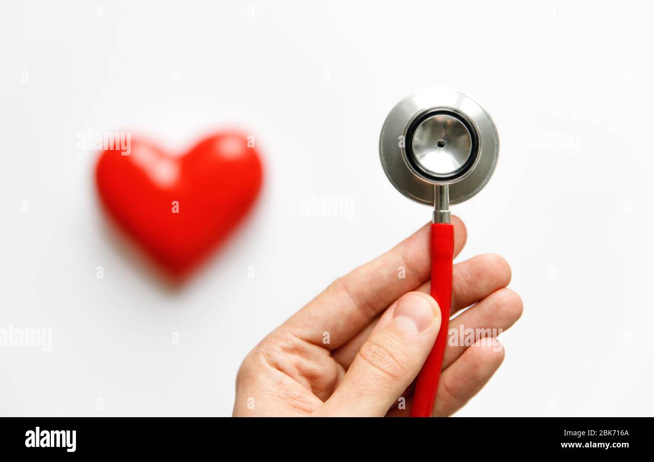 Nahaufnahme der Hand des Mannes, der ein rotes Stethoskop hält - medizinisches Diagnosegerät für Auskultation (Hören) der Töne, die vom Herzen, Bronchien, isola kommen Stockfoto