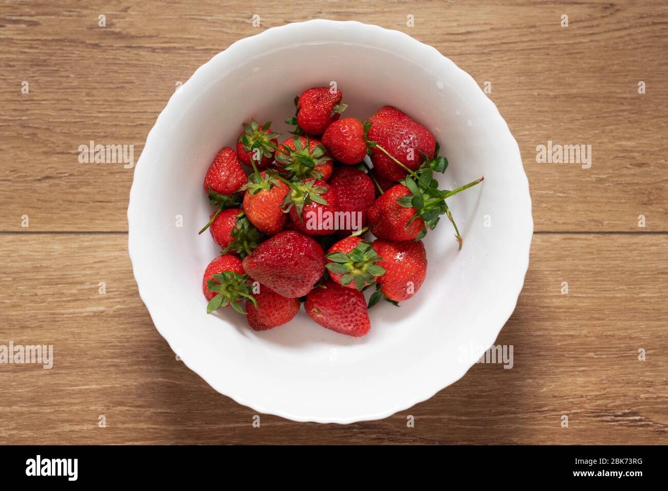 Frisch gepflückte Erdbeeren in einem weißen Tuch auf einem Holztisch, von oben gesehen; ganze saubere und gewaschene Früchte, gesundes Frühstück Stockfoto