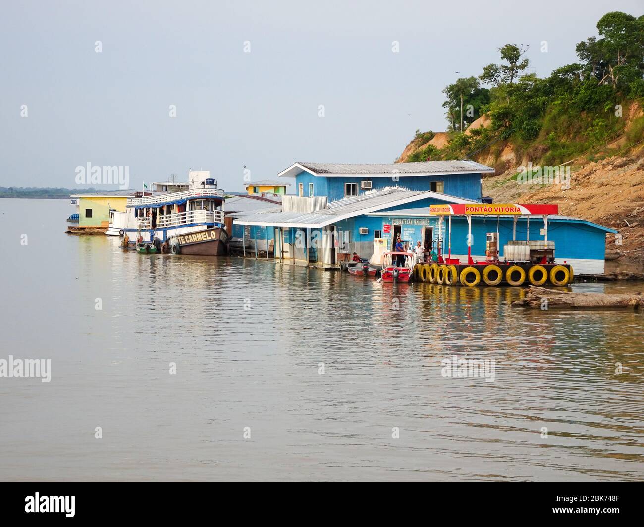 Holzhäuser und ein Boot am Ufer des Flusses, Stockfoto