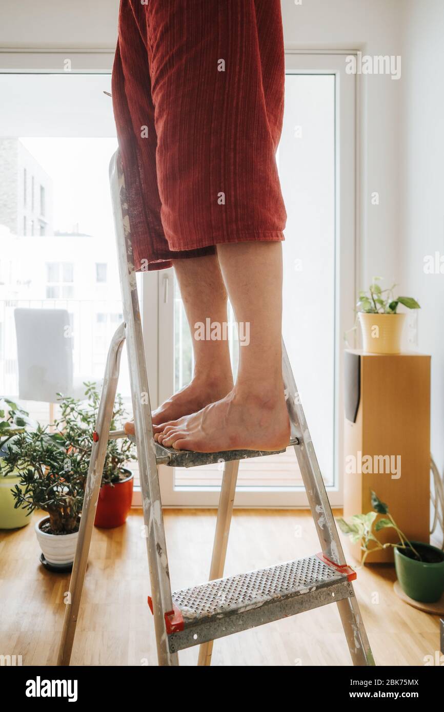 kaukasischer Mann barfuß auf Leiter Stockfoto