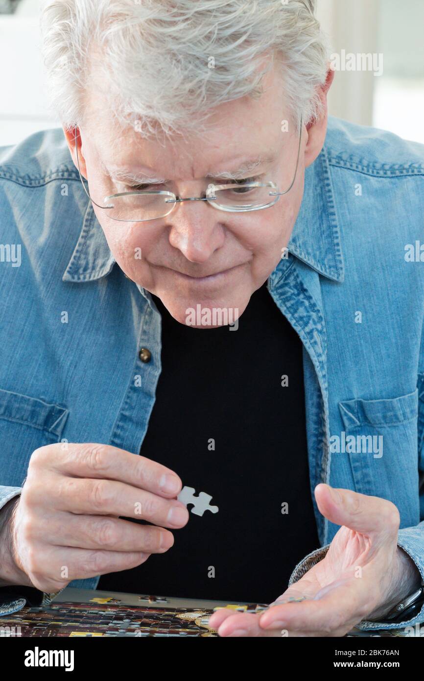 Puzzle wird von einem männlichen Rentner montiert zeigt seine Konzentration und akute geistige Schärfe, USA Stockfoto