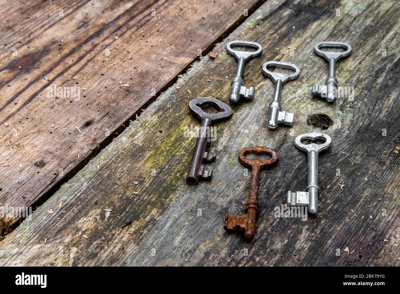 Alte Schlüssel in verschiedenen Größen auf rustikalen verwitterten Holzplanken Stockfoto