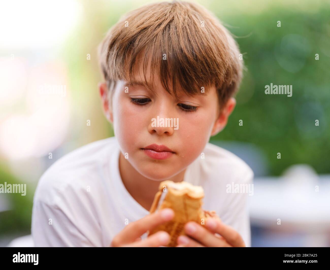 Nahaufnahme Porträt von schönen, niedlich, kleinen Jungen, hält Eis Sandwich in der Hand, Blick auf Eis Stockfoto