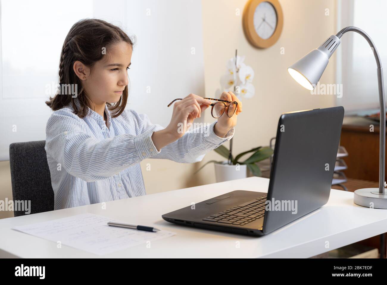 Kleines Mädchen versucht, mit dem Computer mit ihrer Brille zu studieren Stockfoto