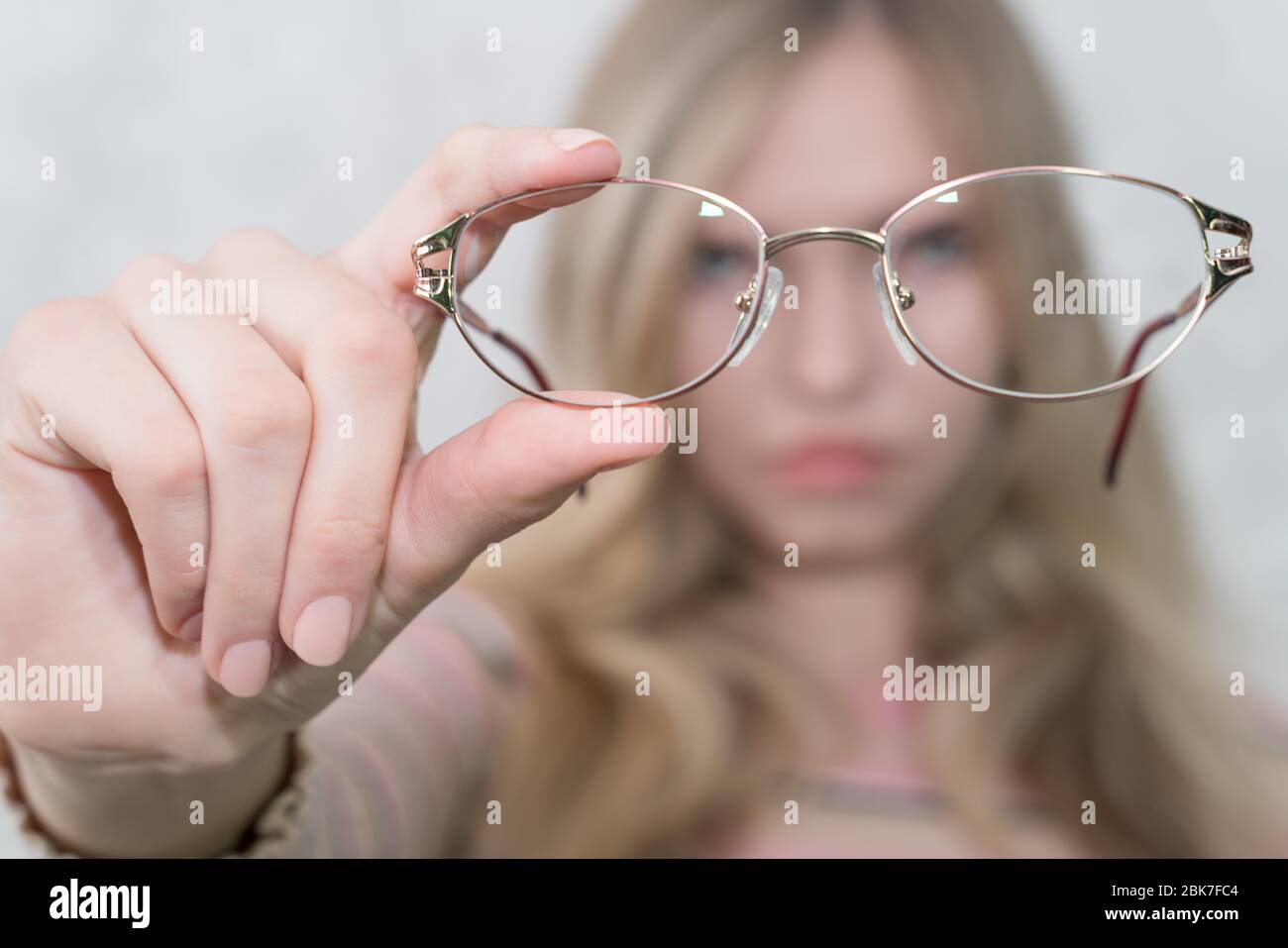 Mädchen hält Brille in den Händen in großer Entfernung von ihrem Gesicht. Gesicht nicht fokussiert Stockfoto