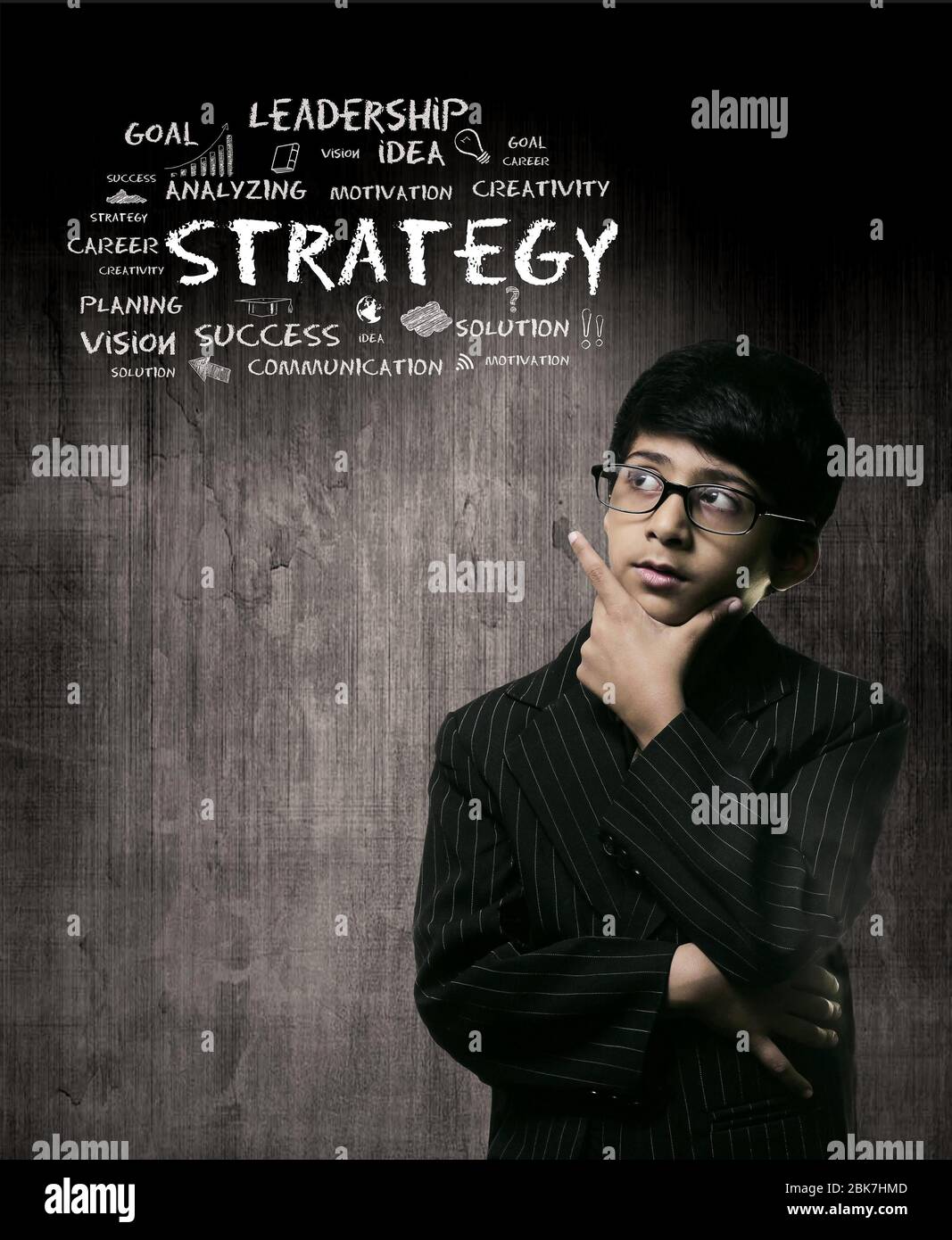 Niedliche intelligente kleine Junge trägt Brille, Hand unter Chin und Denken, während vor EINEM Chalkboard stehen. Denkstrategie Stockfoto