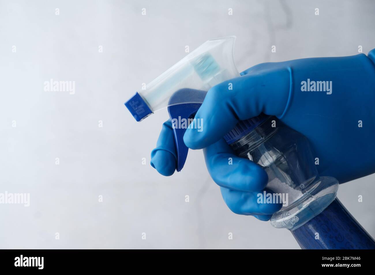 Hand in blauen Gummihandschuhe halten Sprühflasche Stockfoto