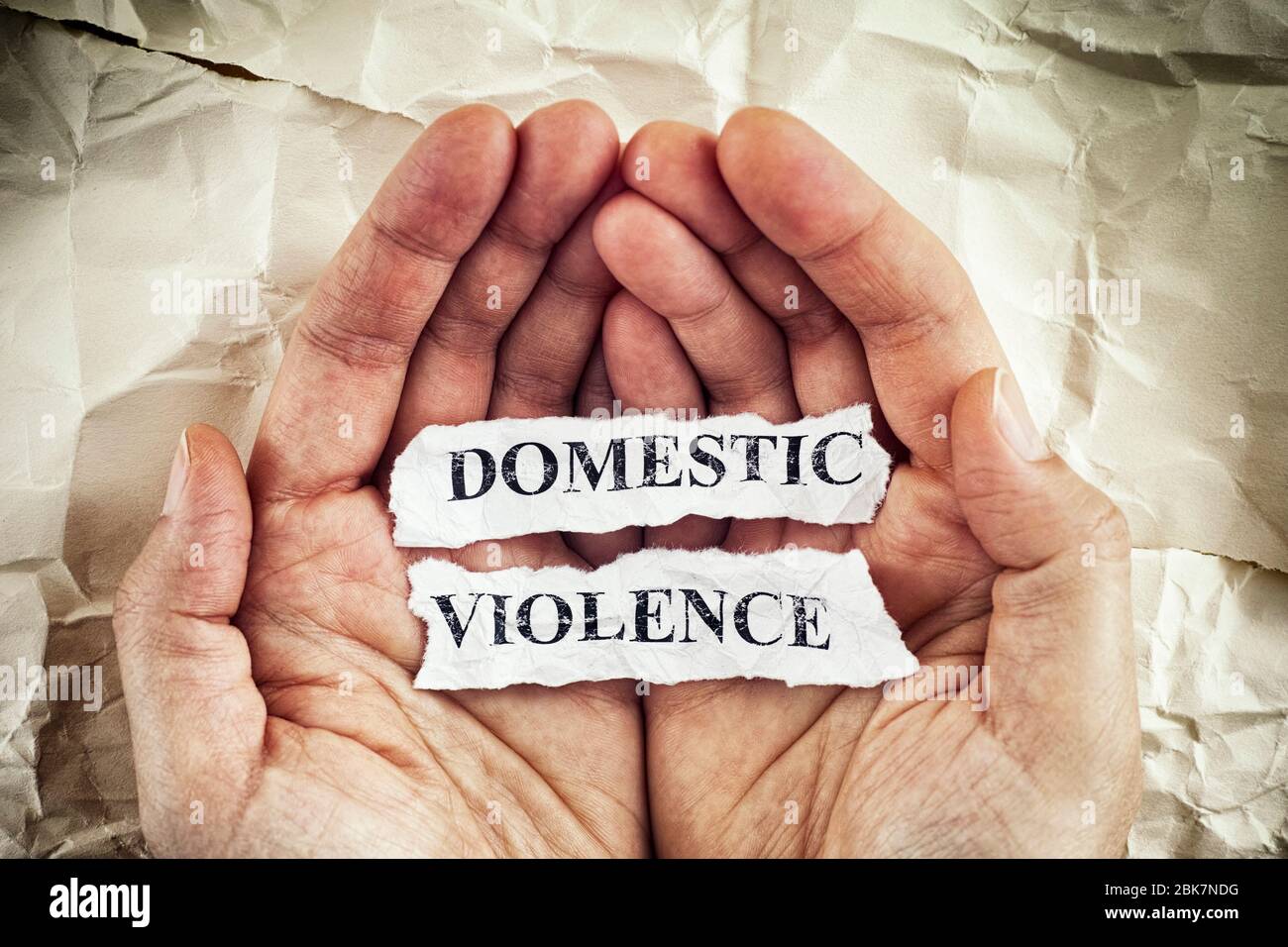 Häusliche Gewalt. Frau, die zerrissene Papierstücke mit den Worten häusliche Gewalt in ihren Handflächen hält. Konzept Bild. Nahaufnahme. Stockfoto