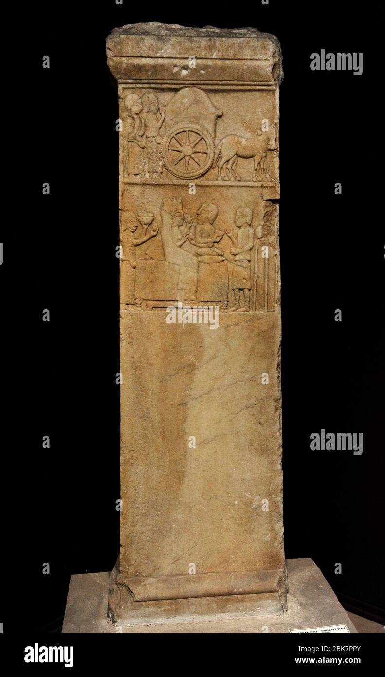 Anatolisch-persische Grabstele, 5. Jahrhundert v. Chr. Marmor. Von Daskylaion (Ergili, Manyassee). Stele mit Darstellung einer Grabkammer in zwei Szenen: Zwei trauernde Frauen gehen hinter einem Trauerkorren (obere Szene). Eine Frau und ein bärtiger Mann sitzen auf einer Couch (untere Szene). Die linke Hand der Frau hält einen Gegenstand, während ihre rechte Hand vom Mann ein Ei erhält. Die Couch wird von Dienern oder Sklaven flankiert. Rechts steht der Slave vor einem auf einem Stativ platzierten Schiff. Links trägt der andere Sklave eine Obstschale. Archäologisches Museum. Istanbul, Türkei. Stockfoto