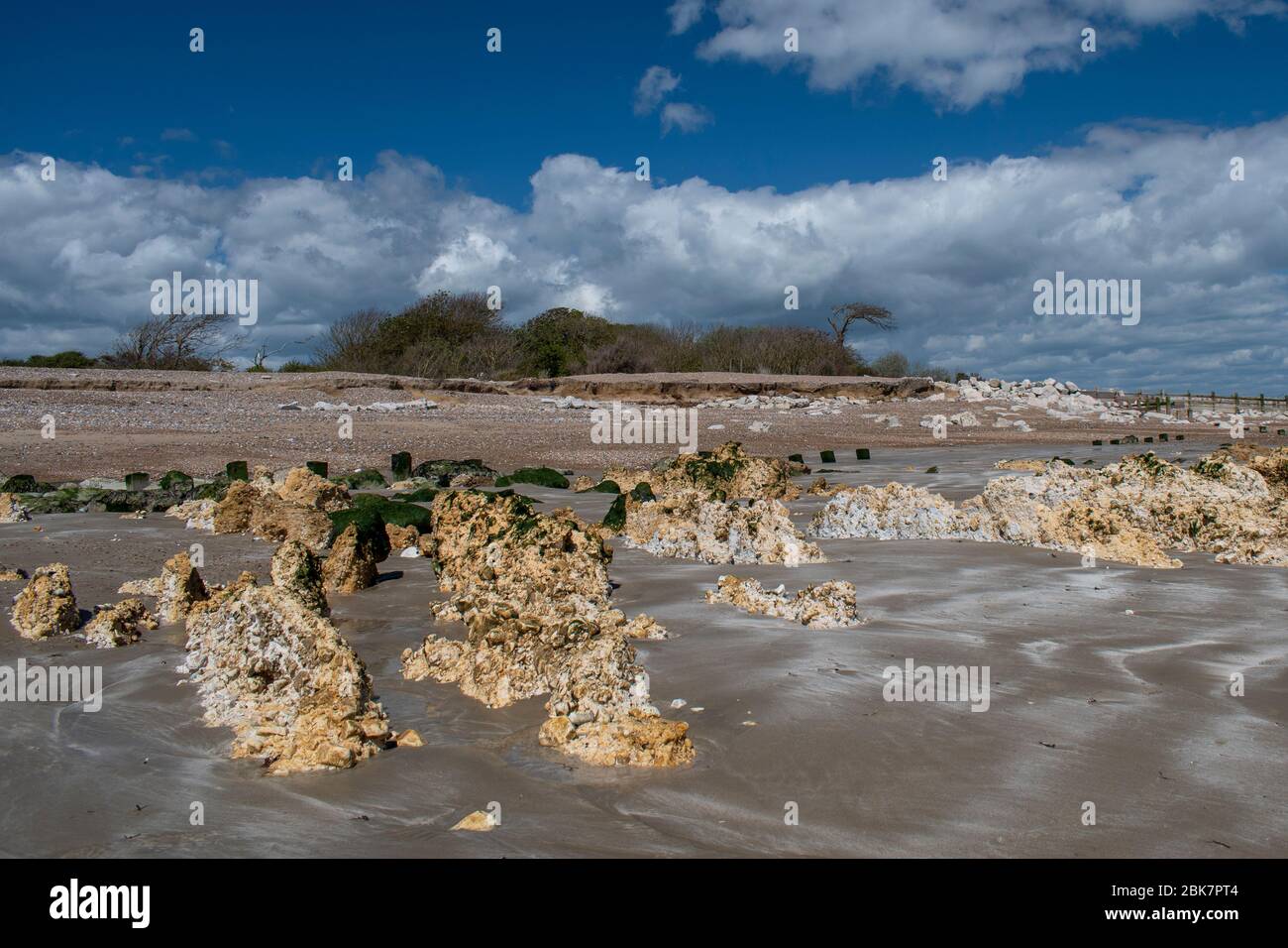 Climping Beach bei Ebbe an einem schönen Frühlingstag mit ungewöhnlichen Steinformationen im Sand. Stockfoto