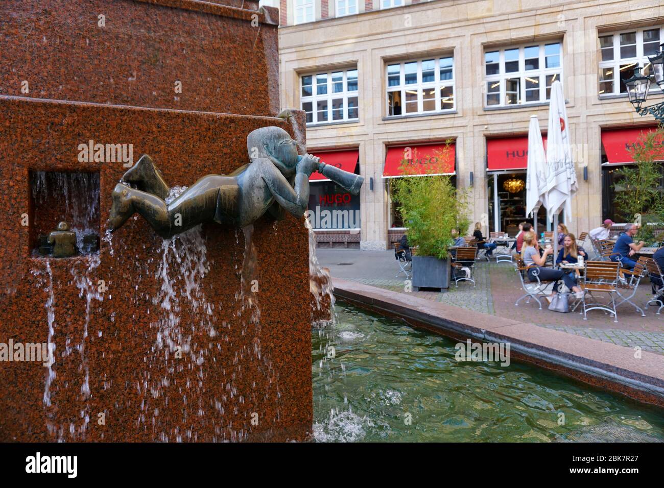 Ausschnitt des Musikbrunnens des Bildhauers Joachim Schmettau, errichtet 1986. Leute sitzen im Kaffeeplatz. Stockfoto