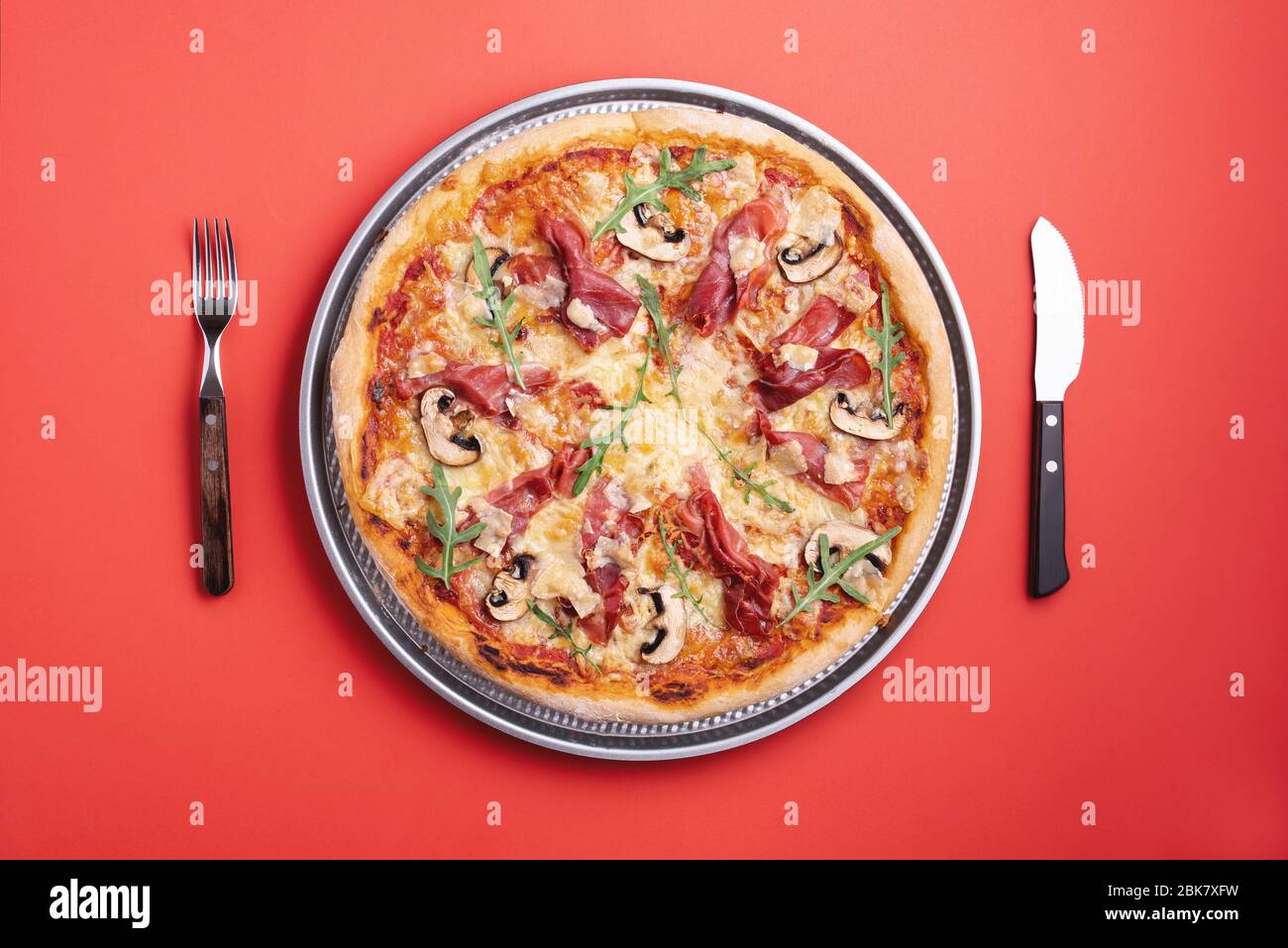 Hausgemachte Pizza mit Prosciutto crudo, Rucola, Mozzarella und Champignons. Flach lag mit einer Schinkenpizza fertig zu essen. Prosciutto und Rucola Pizza top vi Stockfoto