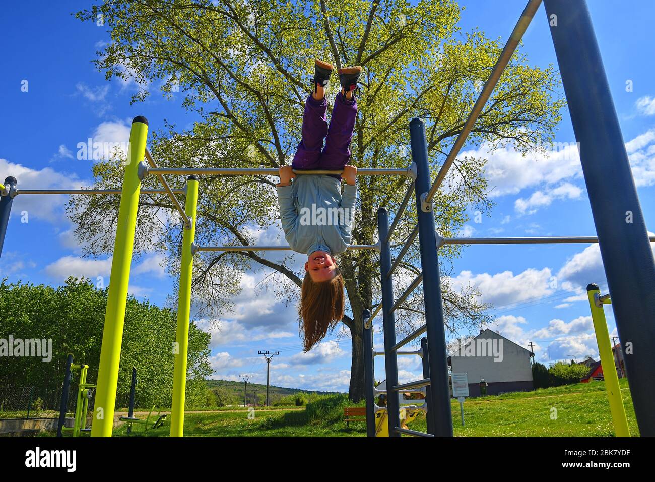 Mädchen Kind hängend kopfüber auf Outdoor-Sport-Spielplatz. Stockfoto
