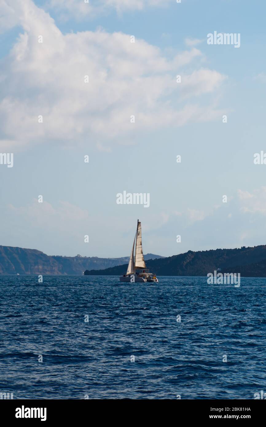 Entspannende Küstenlandschaft mit Segelboot auf der Ägäis in den vulkanischen Inseln Santorinis Stockfoto