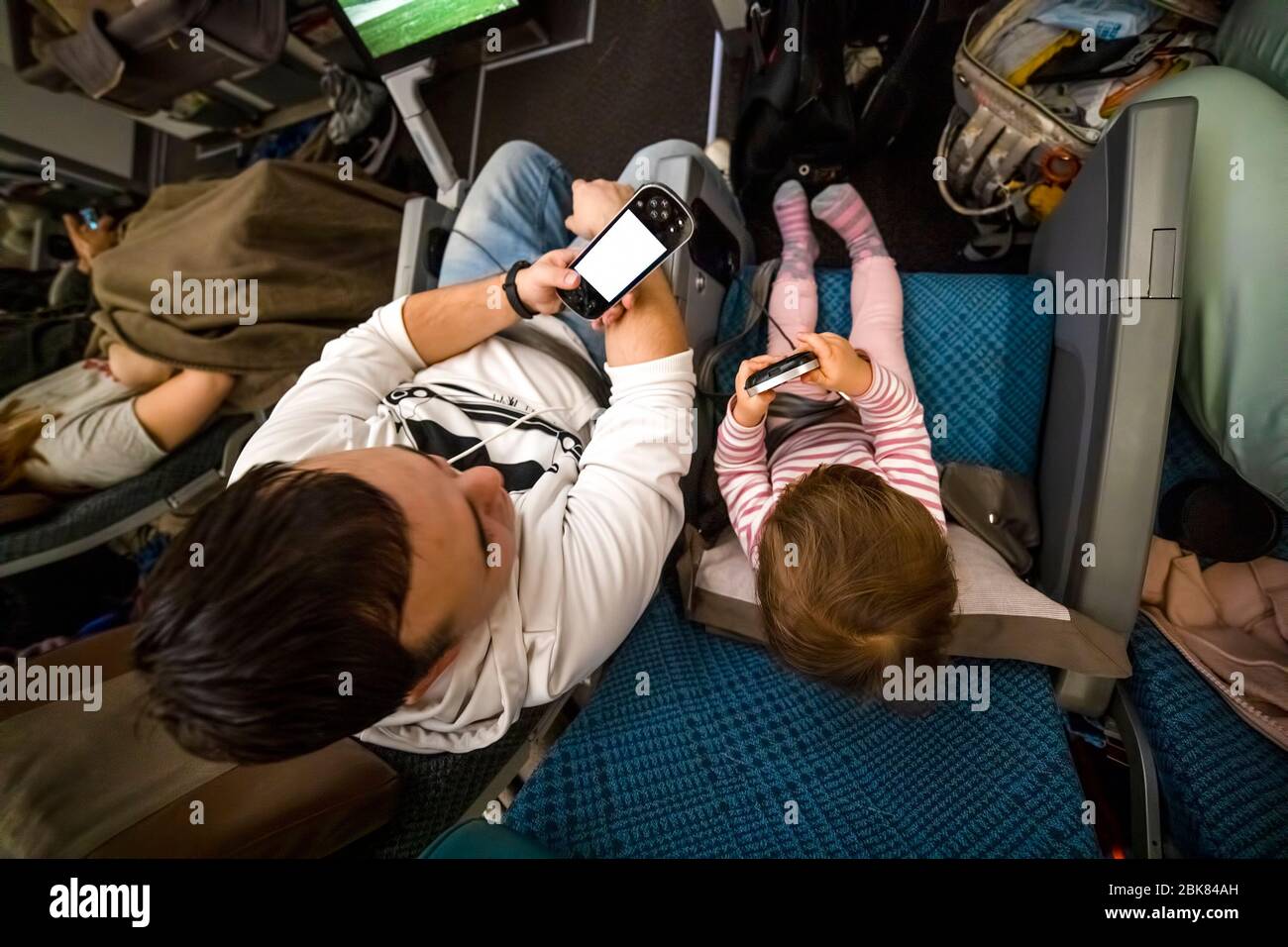 Unterhaltung an Bord des Flugzeugs. Papa und Baby sitzen im Flugzeug in Sesseln und haben Spaß beim Spielen im Multimediasystem consol Stockfoto