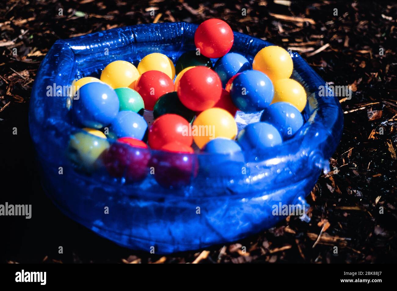 Bunte Kunststoff Kinderkugeln in einem blauen transparenten Planschbecken in einem Garten, Großbritannien Stockfoto