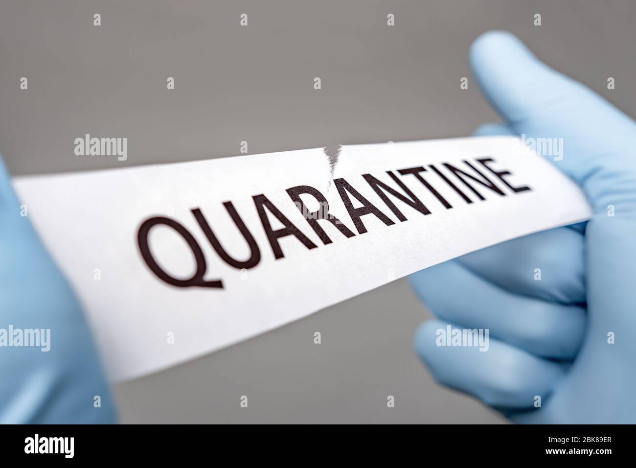 Hände in medizinische Handschuhe reißen ein Stück Papier mit QUARANTÄNE aufgedruckt. Covid-19 Wuhan Novel Coronavirus Pneumonie: COVID-19. Gefährlicher Virus Stockfoto